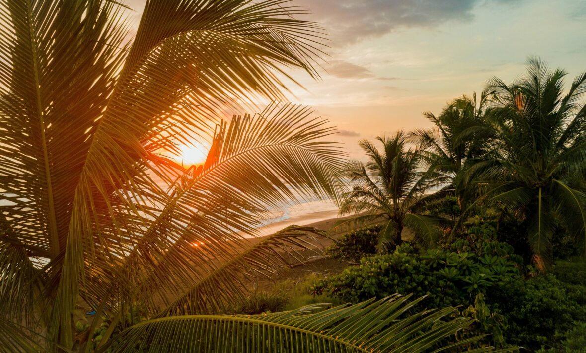 Best places to visit in Costa Rica include a tropical beach at sunset with palm trees.