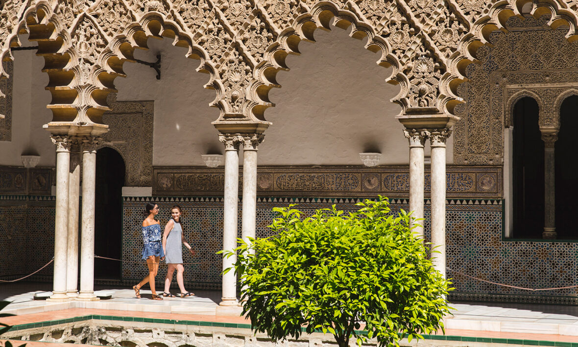 Two women walking in front of an ornate building used as a filming location for Game of Thrones.