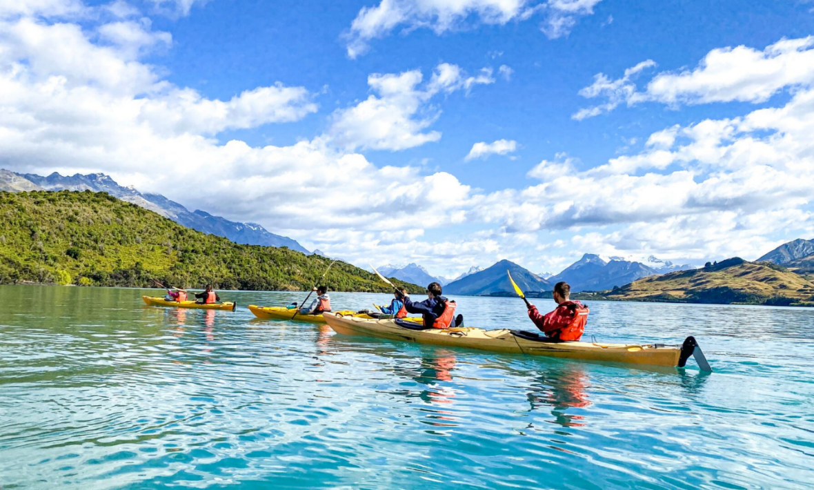 A group of people paddling in kayaks on a lake.