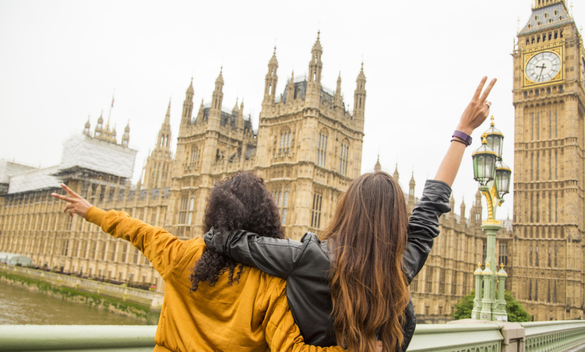 Two young women standing on a bridge overlooking Big Ben in Great Britain.