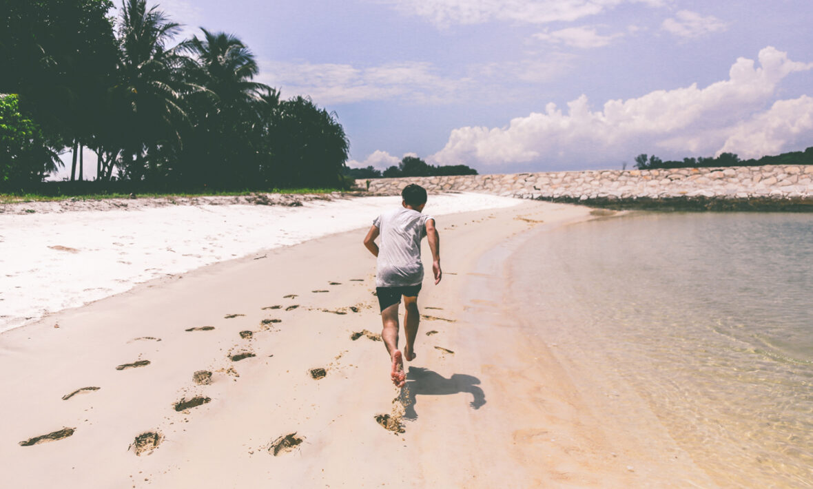 stay fit whilst travelling - guy running on the beach