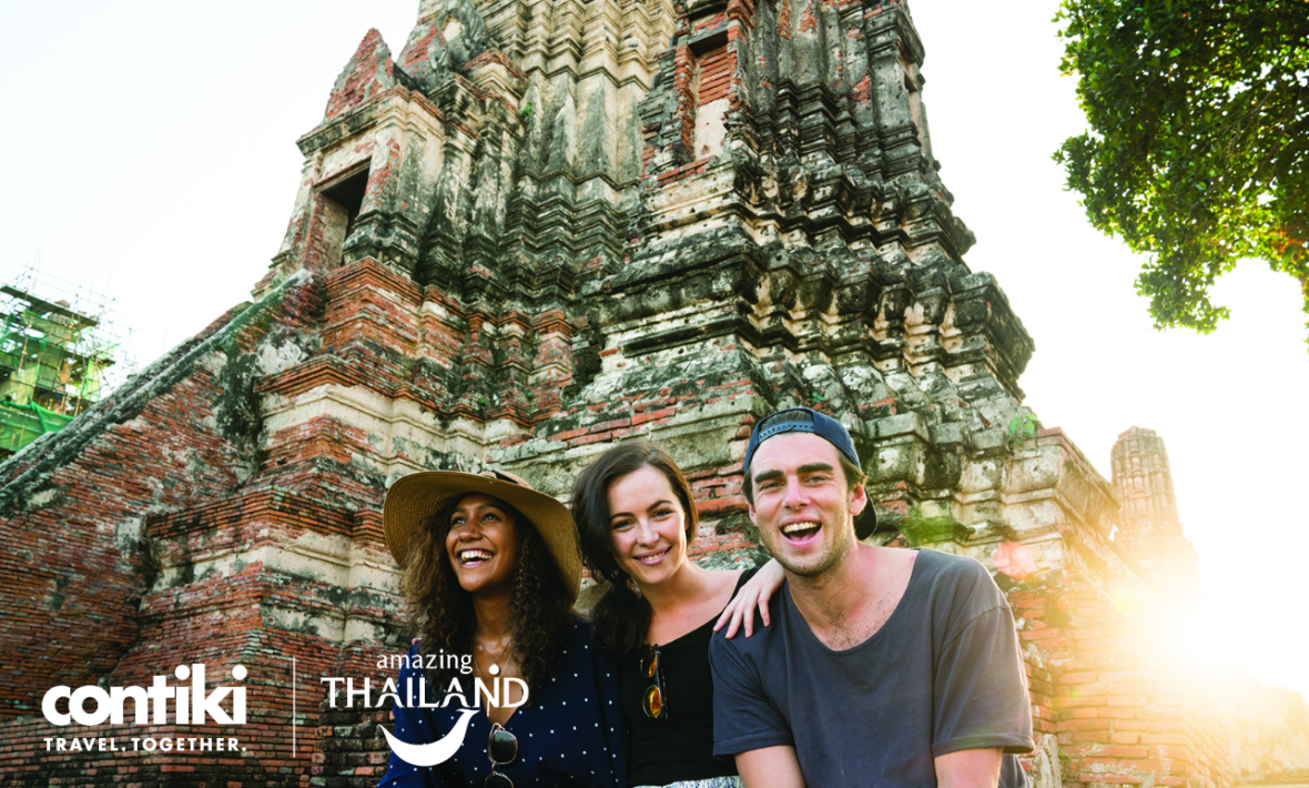 A group of people are posing in front of one of the most beautiful destinations in Thailand, a temple.