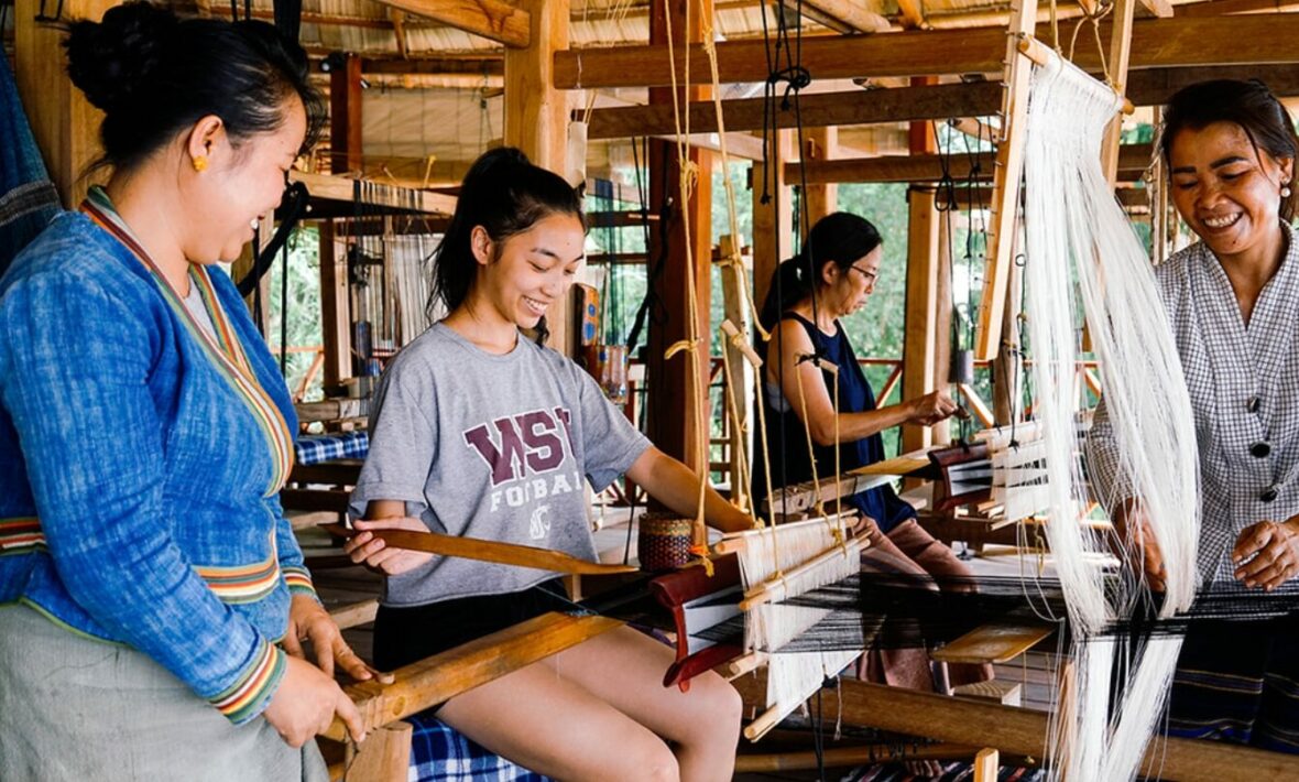 In celebration of International Women's Day, a diverse group of women come together to skillfully work on a weaving loom.