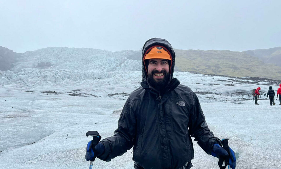 A man is standing in front of a glacier, marveling at the accessibility in Iceland.