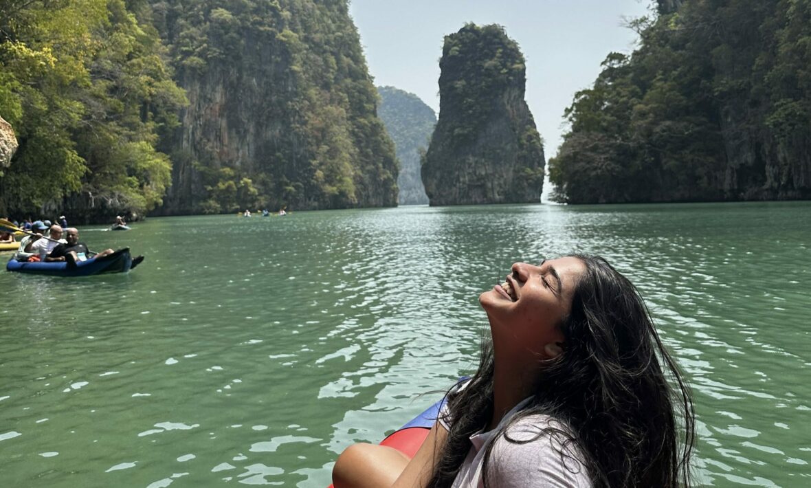 A woman enjoying social travel in Thailand sits peacefully on a red raft, surrounded by the soothing waters.