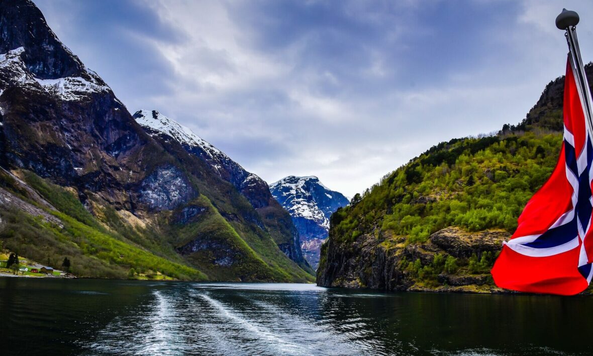 view of fjords in Norway from boat with Norwegian flag