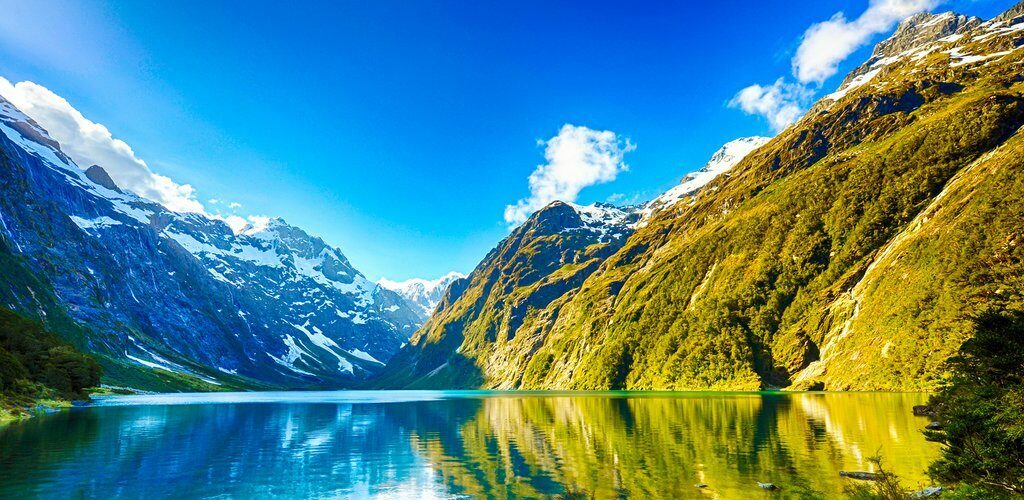 New Zealand Travel Guide: A picturesque lake nestled amidst towering mountains and lush trees.