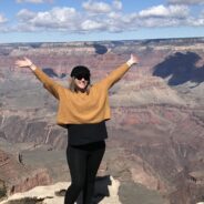 Young woman with her arms in the air standing in front of a canyon