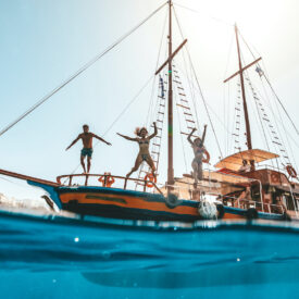 Friends jumping off boat into water having fun in Europe