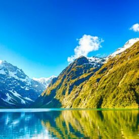 New Zealand Travel Guide: A picturesque lake nestled amidst towering mountains and lush trees.