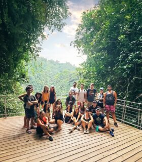 Group shot of young people on a wooden viewing platform in jungle setting.