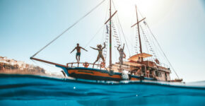 Friends jumping off boat into water having fun in Europe