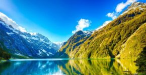 New Zealand Travel Guide: A picturesque lake nestled amidst towering mountains and lush trees.