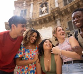 A group of young people laughing in front of one of the best places to visit in Italy.