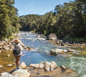 A woman enjoying outdoor activities near a river in New Zealand.