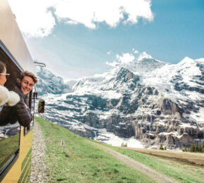 Two young travellers riding a train through alps