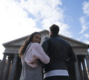 Couple with interlinked arms in front of grand old building