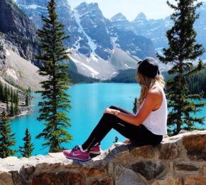 A woman pursues a lifetime of adventures as she sits on a rock overlooking a lake in Banff National Park.