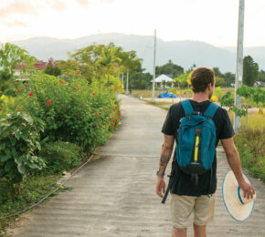 A man traveling with a backpack and a surfboard.