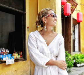 A woman in a white dress standing in front of a building showcasing Hoi An fashion.