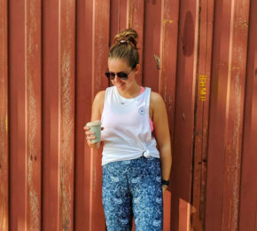 A woman's side hustle involves standing in front of a red wall holding a cup of coffee.