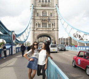 Two women posing in front of Tower Bridge in the UK.