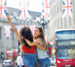 Two young women in london waving at british flags.