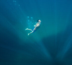 A man is swimming in the water near a dive shop in Borneo.