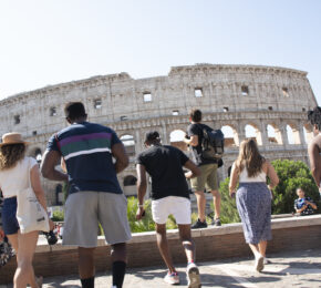 A group of people sightseeing in Rome in front of the colossion.