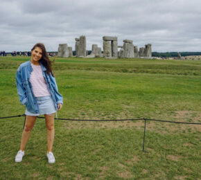 A woman posing in front of Stonehenge during her international exploration.