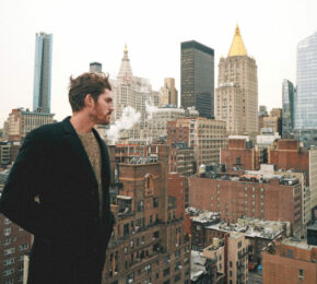 A man experiencing reverse culture shock on top of a building in New York City.