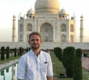 A man poses in front of the Taj Mahal.