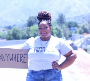 A woman promoting body positivity by holding up a sign that says i'm here for you.