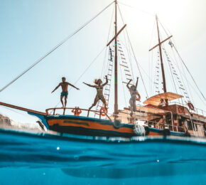 Friends jumping off boat into water having fun in Europe