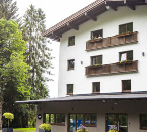 Gasthof Schoneck, a white building with balconies and trees in the background.