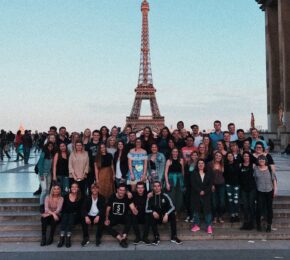 A group of people posing in front of the Eiffel Tower.