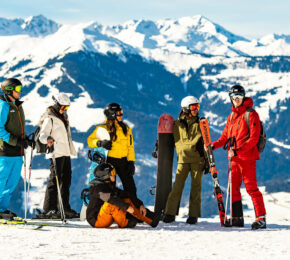 A group of people on a ski trip standing on top of a mountain.