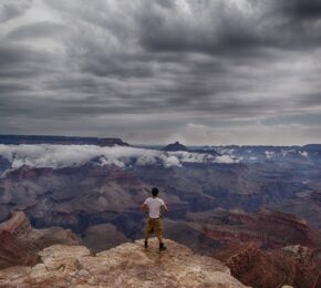 A man taking a professional selfie on a cliff overlooking the grand canyon.