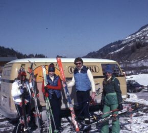 A group of people with skis and a van.