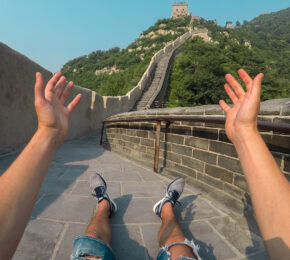 A person with their hands up on the great wall of china.