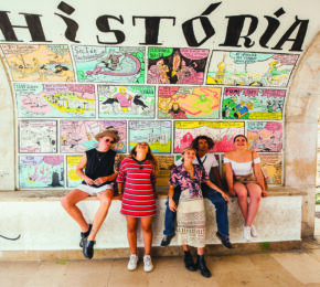 A group of people capturing local experiences in front of a mural.