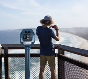 A posed man standing at the edge of a cliff overlooking the ocean.