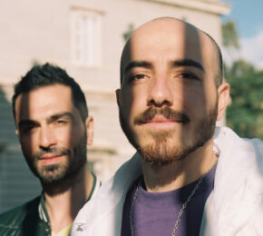 Two men from Rainbow railroad standing next to each other in front of a building.