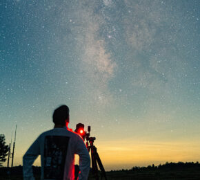 A man using a telescope to observe the sky for stargazing.