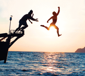 Two digital nomads jumping off a boat in Thailand.