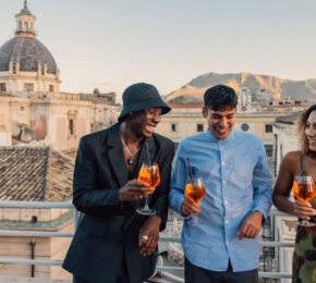 A group of people enjoying a 30th birthday trip on a rooftop with drinks.