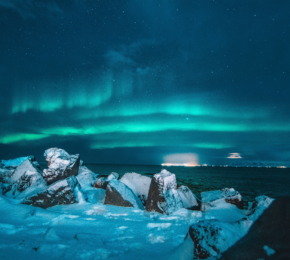 The aurora borealis lights up the sky over a rocky shore during a week in Iceland.