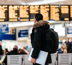 A man with a backpack carrying travel adapters in a train station.