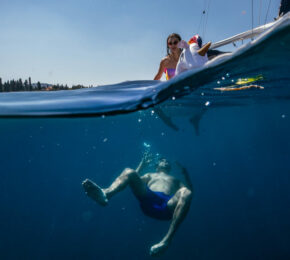 A woman is swimming in the water near a boat.