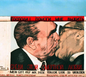 A captivating mural depicting two men kissing skillfully painted on a colorful Berlin wall.